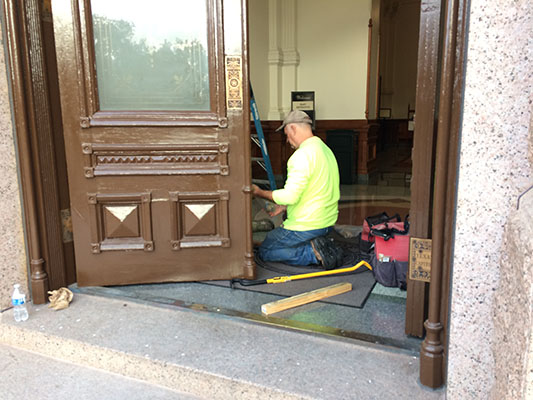 Four view of workers repairing the Capitol door.